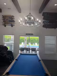 Game room with blue felt pool table and chandelier
